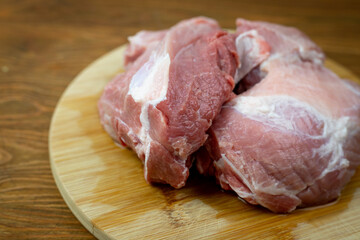 Mięso z łopatki wieprzowej bez kości. Surowe mięso leżące na drewnianej desce. Idealne mięso do gulaszu.  - obrazy, fototapety, plakaty
