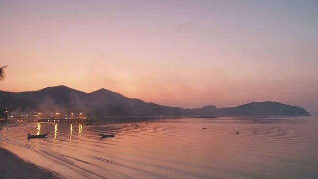 Pink sunset on tropical island sandy beach. Aerial sea shore coast with mountain range silhouette. Fishing boats in ocean bay. Summer holiday vacation travel. Nature landscape background. Drone land