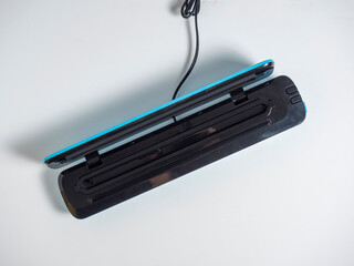 close-up of an open vacuum packer isolated on a bright blue background. A machine for preserving the freshness of products. Flat lying, top view.