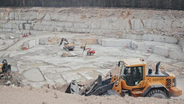 Tracking shot of loader driving along haul road in active granite quarry
