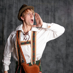 A young man in a national Bavarian suit with shorts on suspenders and a hat. - 459251381