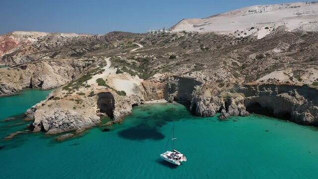 Aerial drone video of beautiful scenic rocky cove and beach of Tsigrado with caves and crystal clear emerald sea, Milos island, Cyclades, Greece