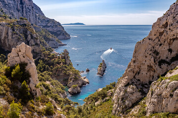 Un bateau part au large et quitte les calanques de Marseille sur une belle mer bleue © Yannick