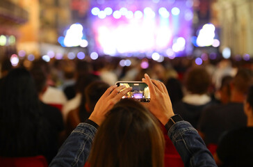 girl shooting a video with her smartphone during an outdoor concert with a lot of audience