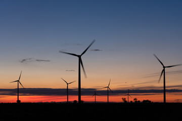 Fototapeta premium Production of electrical energy with wind mills in a sustainable way with renewable energies at sunset