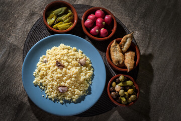 Plate with migas, accompanied by anchovies, radishes, fried peppers and olives, overhead view.