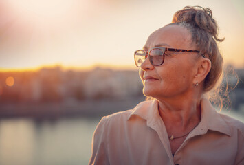 Close up portrait of stylish beautiful mature senior woman wearing glasses 60 years old looking to...