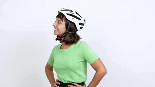 Young woman with bike helmet over isolated background posing with arms at hip and laughing over isolated background
