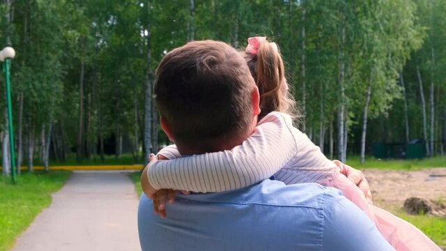 Happy father carrying around his neck and hugging daughter 4-5 years old hugs and circles in the park