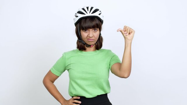 Young woman with bike helmet over isolated background doing bad signal over isolated background