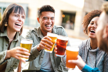 Group of happy multiethnic friends drinking and toasting beer at brewery bar restaurant - Beverage concept with men and women having fun together outside - 459257961