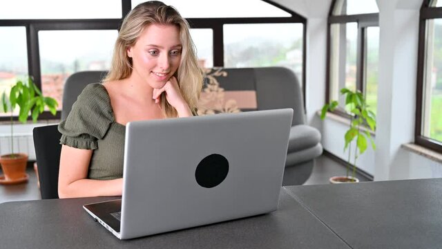 Beautiful young woman in casual clothing using laptop and smiling while working  from home to prevent spreading covid 19 desease