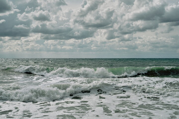 Fototapeta premium Running waves on the beach, sunny and windy summer day with cloudy skies, perfect surfing weather. Sea view