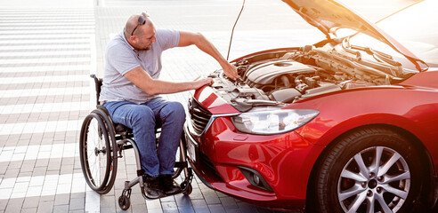 Fototapeta premium Disabled man in wheelchair check engine his car at parking