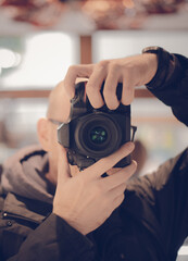 Close up portrait of Man pointing a DSLR camera with bright background