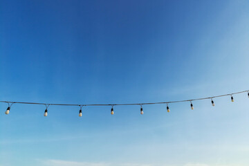 Beautiful clear sky with light bulbs hanging on a rope in park at Krabi Thailand and soft clouds make you feel and see the good weather in the morning of a new day. Ideas: the feeling of fresh weather