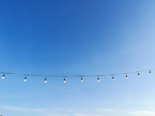 Beautiful clear sky with light bulbs hanging on a rope in park at Krabi Thailand and soft clouds make you feel and see the good weather in the morning of a new day. Ideas: the feeling of fresh weather