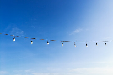 Beautiful clear sky with light bulbs hanging on a rope in park at Krabi Thailand and soft clouds make you feel and see the good weather in the morning of a new day. Ideas: the feeling of fresh weather