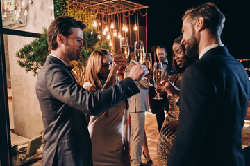 Group of people in formalwear communicating and smiling while spending time on luxury party