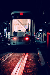 Plakat Tram at night with rails being lit with red light