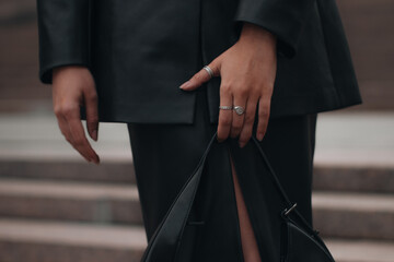 Female hands with silver rings with black handbag. Style, design of women's clothing and...
