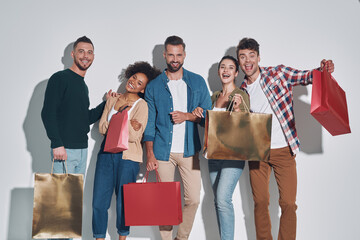 Group of young beautiful people in casual clothing carrying shopping bags and smiling