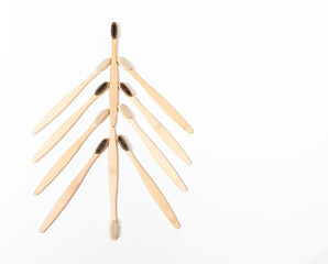 Eco friendly bamboo toothbrushes for dental care, personal hygiene, laid out as Christmas tree on white. Top view.
