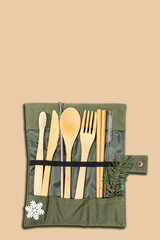 Christmas set of eco friendly cutlery and hygiene products in textile case with snowflake and fir twig on beige,