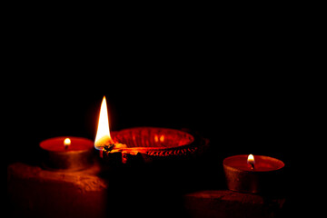 Clay diya lamps and aluminium cup candle lit during diwali celebration with dark background