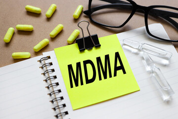 MDMA Medicine doctor hand working. Data Mining .sticker attached to a notebook on aa wood...