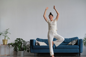 woman trying to stand in tree pose, amateur incorrectly performs yoga exercises