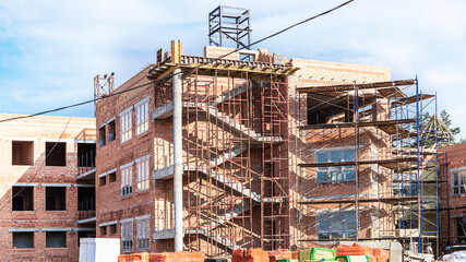 Thermal insulation of a red brick house with mineral wool. The use of scaffolding when building a house.
