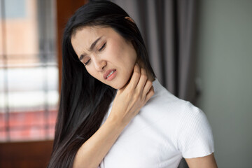 Unvaccinated asian woman having sore throat from flu or coronavirus infection