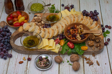 Appetizer board with bread, olive oil, nuts, tomatoes, grapes on wooden table