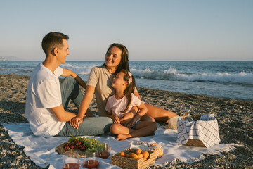 Summer family leisure picnic lunch with fruits by the seaside. Happy people eating healthy food on...