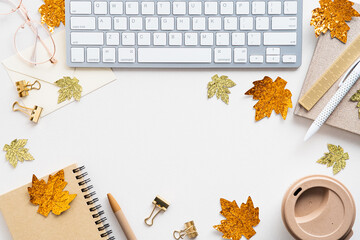 Autumn desk with keyboard, coffee cup, notebook, maple leaves decor on white background. Top view, flat lay home office table, feminine workspace