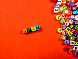 Colorful alphabet beads with text SPAM on red background.