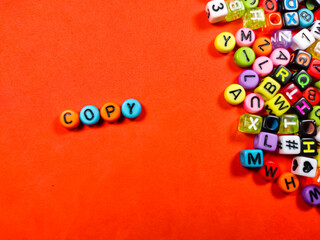 Colorful alphabet beads with text COPY on red background.