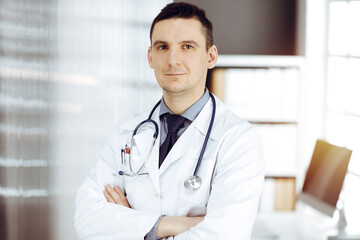 Male doctor standing straight in sunny clinic. Perfect medical service in hospital - 459277910