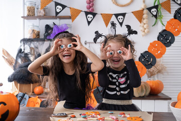 two diverse kids girl in costume of witch, having fun at home in kitchen, celebrating Halloween