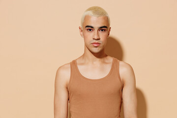 Young stylish serious blond latin american hispanic gay man 20s with make up in beige tank shirt...