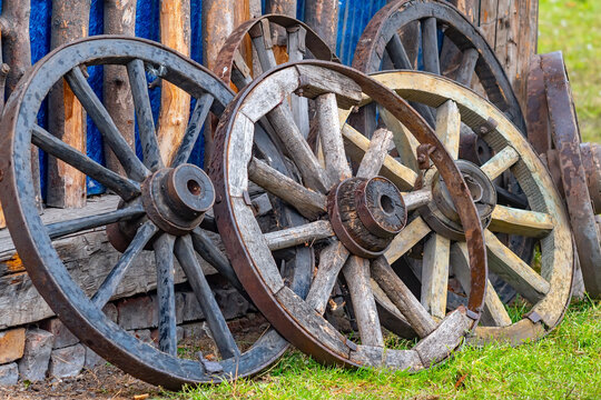 several replacement old and new wheels from the cart, carriages are on the street of the rural yard near the wall of the barn