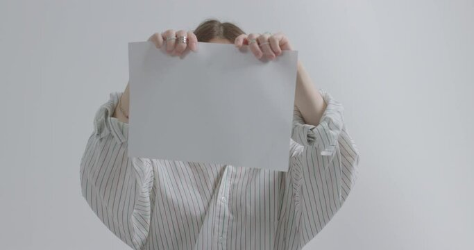 Girl tears a sheet of paper on a white background. Girl aggression due to bullying.