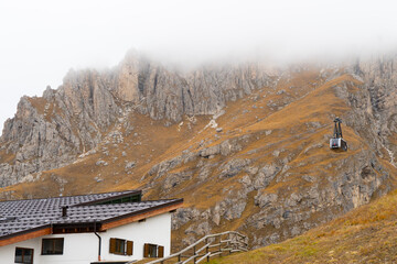 Fototapeta na wymiar Station of cable car way to mountains. Long distance cable car across the rock mountain with fog at Dolomites national park,Italy.
