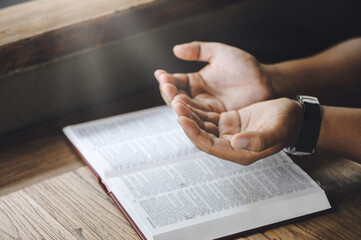 Christian man hand praying to god with the bible. believe in goodness. Holding hands in prayer on a...
