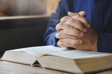 Christian man hand praying to god with the bible. believe in goodness. Holding hands in prayer on a wooden table for god blessing to wishing have a better life. pray and worship concept.