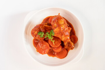 Chicken wings simmering in tomato and chili sauce. 