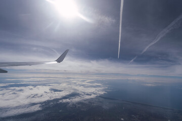 ala de un avión visto desde el aire por la ventanilla  - obrazy, fototapety, plakaty