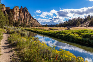 Fototapeta na wymiar The river is flowing among the rocks. Colorful Canyon. Reflection of the yellow rocks in the river. Amazing landscape of yellow sharp cliffs. Smith Rock state park, Oregon
