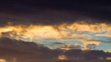 Fototapeta na wymiar Teintes mordorées sous la base de nuages de moyenne altitude, pendant le coucher du soleil